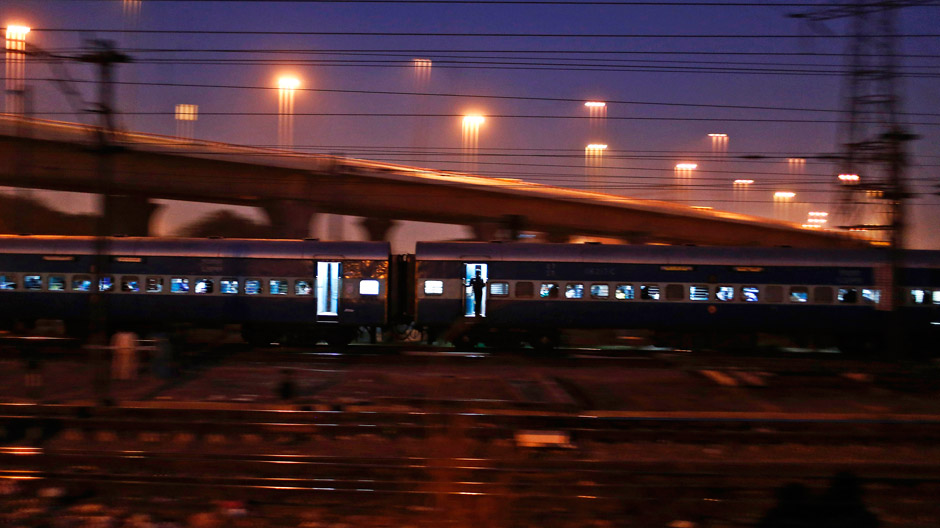 A commuter stands on the doorsteps of a moving train in New Delhi March 6, 2014.