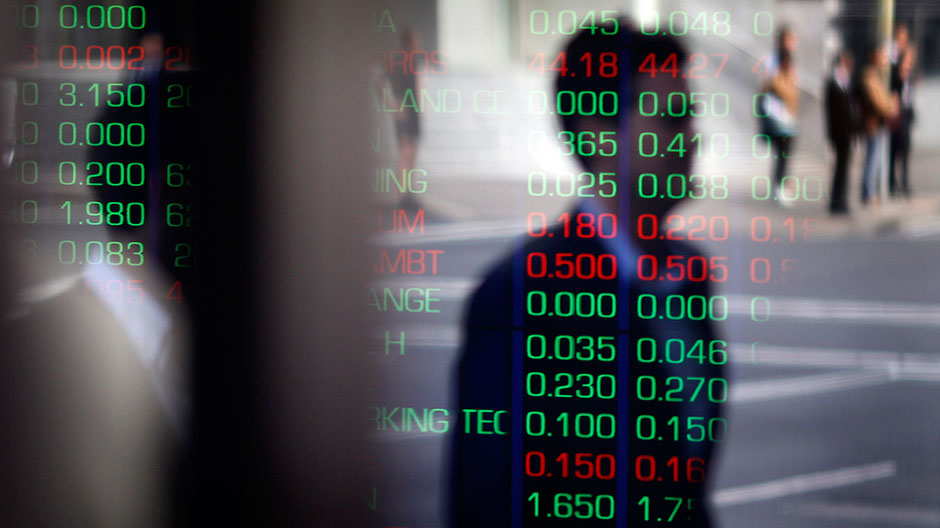 A man is reflected in a window as he walks past the indicator boards at the Australian Stock Exchange in Sydney August 11, 2011.
