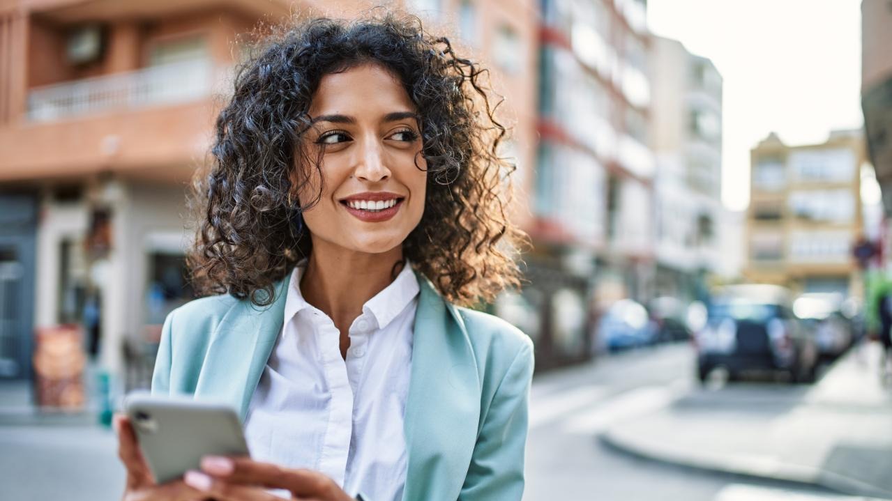 Professional using a smartphone in a city setting, representing legal professionals leveraging CoCounsel AI for contract review, compliance, and legal workflows.